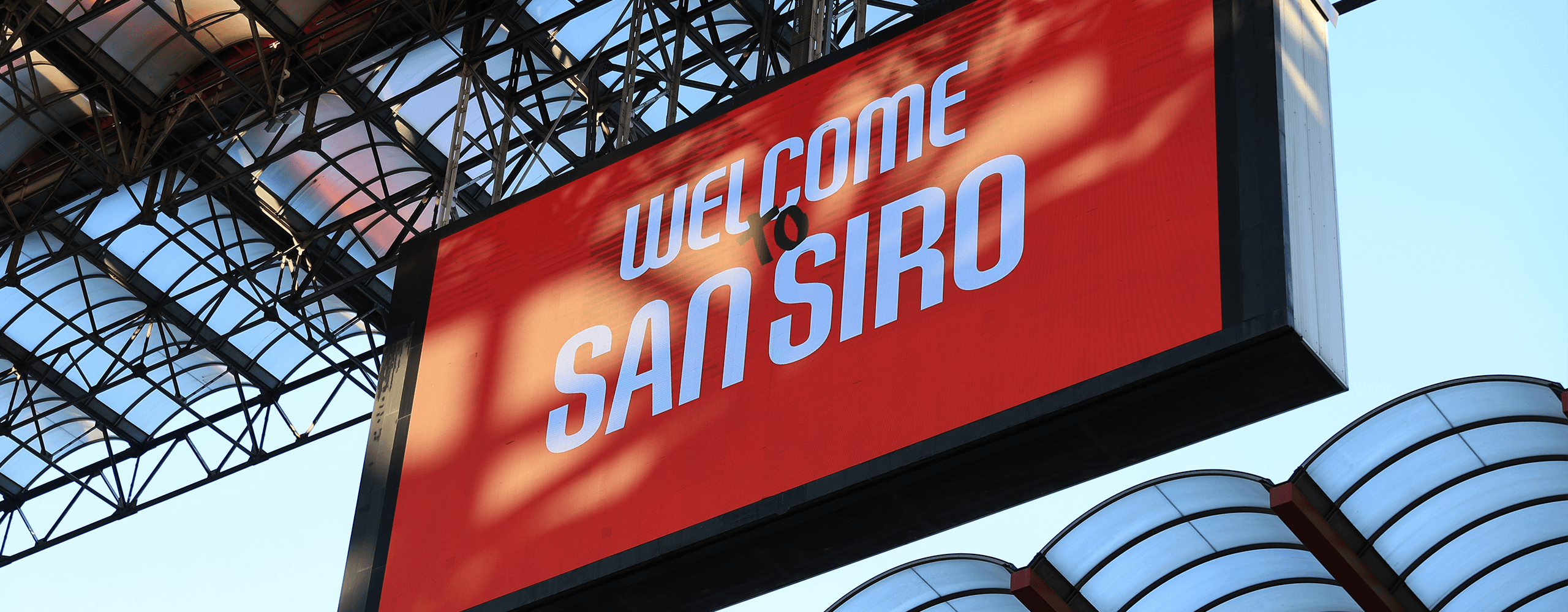 Red big screen with ‘Welcome to San Siro’ text and stadium roof structure